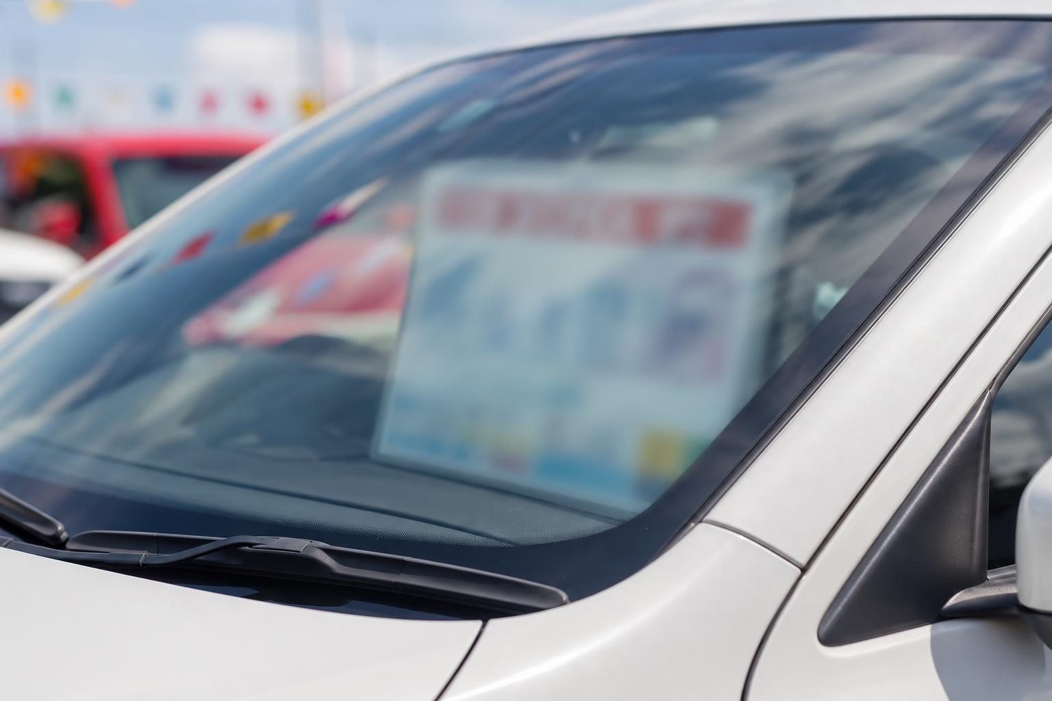 中古車販売店の店頭に並ぶコンパクトSUVと、フロントガラスに貼られた価格ボード