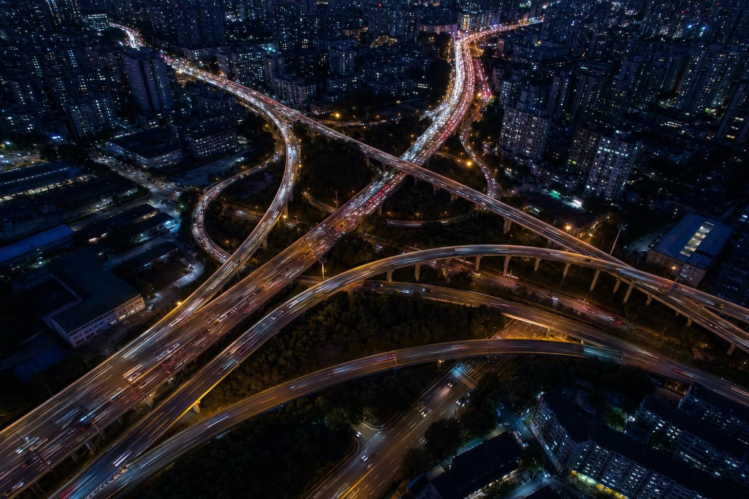 夜の都市高速のジャンクションを見下ろした、車のライトが流れる俯瞰のイメージ
